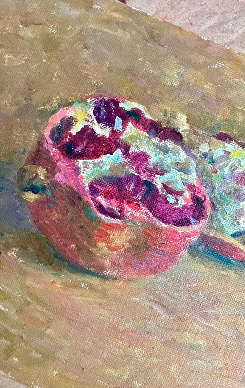 May include: A close-up of a painting of a halved pomegranate with red and white seeds on a brown canvas background.