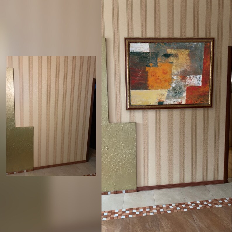 May include: A close-up of a wall with beige and brown striped wallpaper. A framed abstract painting with orange, red, and yellow colors hangs on the wall. The painting is centered on the wall and is surrounded by a brown frame.