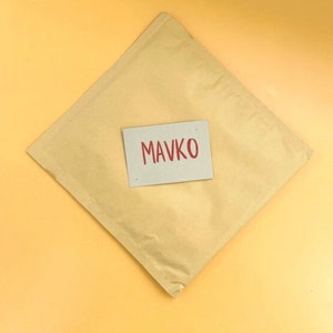 May include: A brown paper envelope with a white card on top. The card has the word "MAVKO" written in red.