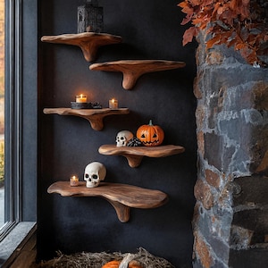 May include: A set of five wooden floating shelves with a dark finish, mounted on a black wall. The shelves are decorated with Halloween-themed items, including candles, skulls, and a carved pumpkin. A decorative lantern sits on the top shelf.