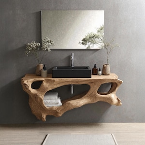 Puede incluir: Un mueble de baño moderno con un diseño de borde vivo de madera natural. Cuenta con un lavabo rectangular negro, un grifo cromado y un espejo grande. El mueble tiene un estante con toallas blancas dobladas y objetos decorativos.