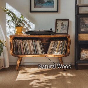 May include: A wooden record player console with a built-in storage compartment for vinyl records. The console is made of natural wood and features a turntable on top. The text "Natural Wood" is visible on the console.