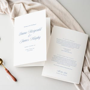 May include: A folded wedding invitation in cream with navy blue text. The invitation is open, displaying the names Emma Fitzgerald and James Murphy, the wedding date, and location. Includes a note from the couple and a loving memory section.