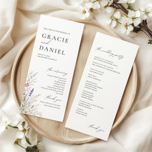 Peut inclure: Deux programmes de mariage sur un plateau en bois, avec les noms "Gracie et Daniel" et les détails du mariage. Le programme de gauche a des accents floraux à l'aquarelle. Le programme de droite liste le cortège. Les deux disent "merci".