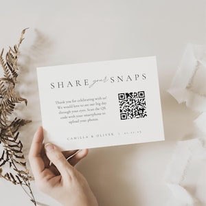 以下が含まれることがあります： 「SHARE your SNAPS」の文字とQRコードが印刷されたクリーム色のカード。イベントの写真の共有をゲストに促すメッセージが記載されています。「CAMILLA & OLIVER」の名前と日付も印刷されています。