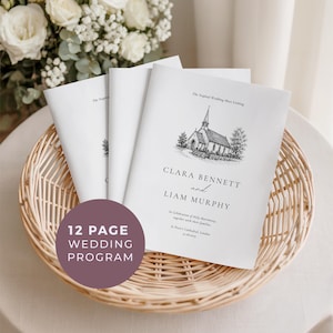 Könnte beinhalten: Weiße Hochzeitskarten mit einer Kirchenillustration und den Namen "Clara Bennett und Liam Murphy" in einem Weidenkorb. Die Programme sind 12 Seiten lang. Ein Strauß weißer Blumen befindet sich im Hintergrund.