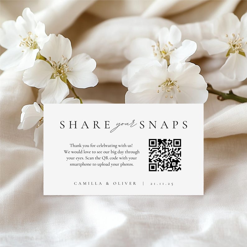 以下が含まれることがあります： 「SHARE your SNAPS」の文字とQRコードが記載された白いカード。カードには「Thank you for celebrating with us!」と「CAMILLA & OLIVER | 21.11.25」の文字も含まれています。背景には白い花があります。