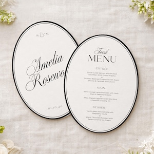 Peut inclure: Deux cartons de menu de mariage ovales avec des bordures noires. L'un des cartons indique "Amelia Rosewo" avec "S & M" au-dessus et "01.10.26" en dessous. L'autre carton indique "Food MENU" avec une liste d'éléments de menu.