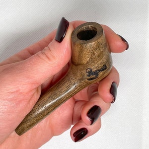 May include: A brown wooden smoking pipe with the word "Reggae" engraved on the side.