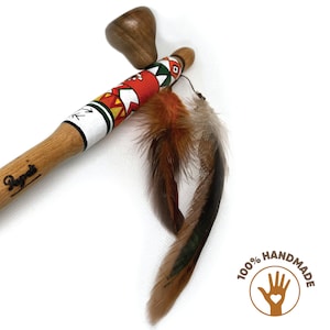 May include: A wooden hand-painted stick with a round wooden top and feathers attached. The stick is decorated with geometric patterns in red, yellow, green, and black. The text "100% HANDMADE" is visible in the lower right corner of the image.