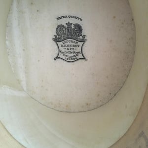 May include: Inside view of a cream-colored hat with a visible brim. The hat's interior features a faded, circular label with the text "EXTRA QUALITY" and "LINCOLN BENNETT & CO - Sackville Street, PICCADILLY, LONDON."