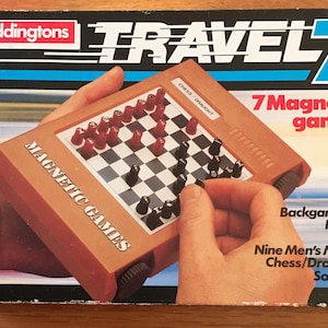 May include: A vintage Waddingtons Travel 7 magnetic games set. The box is black and blue with the words "TRAVEL 7" in white and blue. The set includes a brown magnetic game board with red and black game pieces. The box lists the games: Backgammon, Nyout, Ludo, Nine Men's Morris, Chess/Draughts, and Solitaire.