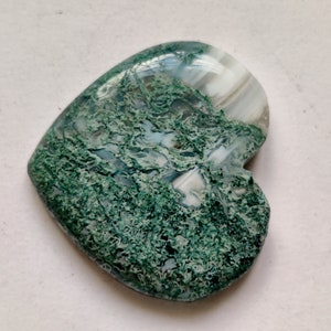 May include: A heart-shaped green and white agate cabochon with a swirling pattern. The stone is polished and has a smooth surface.