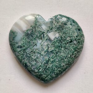May include: A heart-shaped green and white agate stone with a swirling pattern. The stone is polished and smooth.
