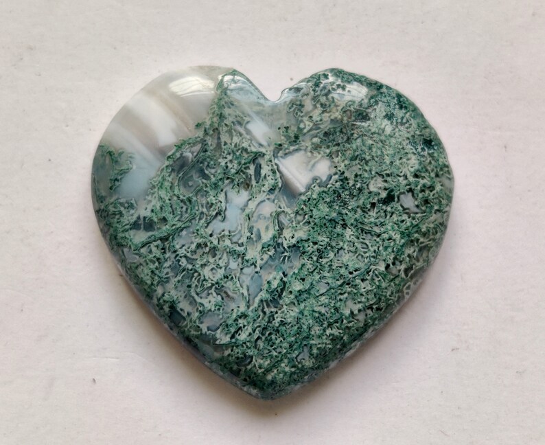 May include: A heart-shaped green and white agate stone with a swirling pattern. The stone is polished and smooth.