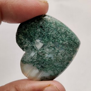 May include: Green moss agate heart shaped stone with white and green patterns.