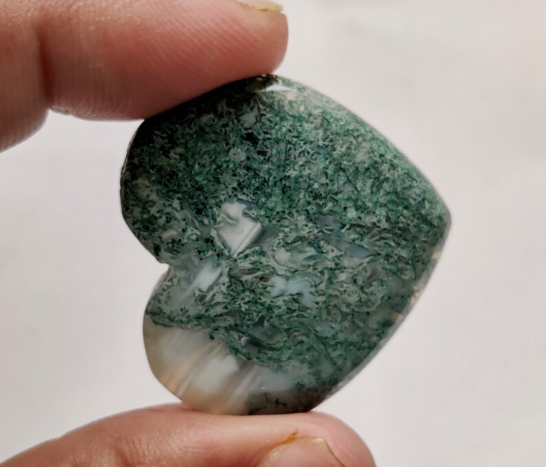 May include: Green moss agate heart shaped stone with white and green patterns.