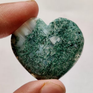 May include: A heart-shaped green and white agate stone with a swirling pattern.