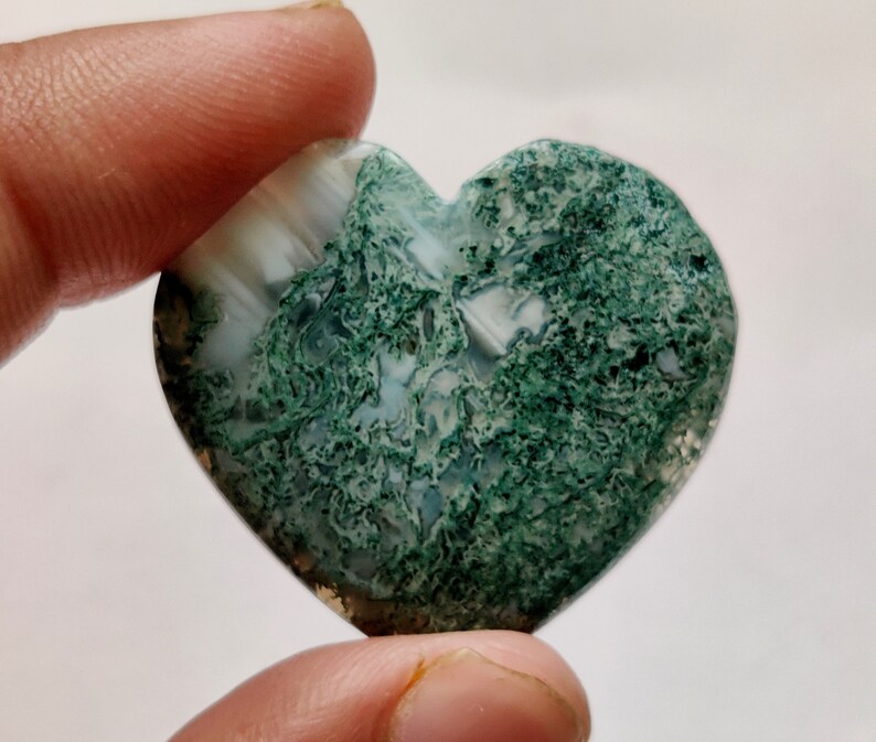 May include: A heart-shaped green and white agate stone with a swirling pattern.