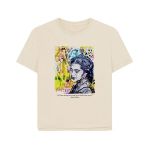 Può includere: T-shirt color crema con un ritratto colorato di una donna con gli occhiali. La grafica include il testo "IHO BC1" e una citazione di Rosa Parks: "Tutto quello che facevo era cercare di tornare a casa dal lavoro."