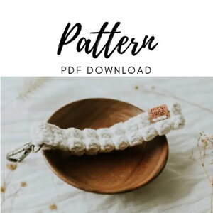 May include: A white crocheted strap with a brown label that says "North Point" in white text. The strap is in a wooden bowl.