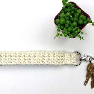 May include: A white crocheted key chain with a silver key ring and three keys attached.