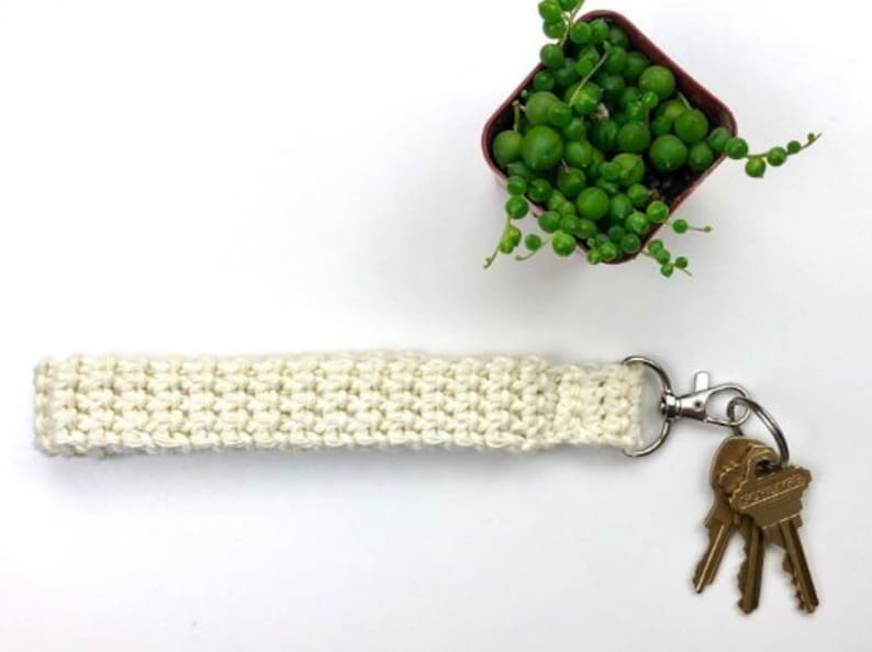 May include: A white crocheted key chain with a silver key ring and three keys attached.