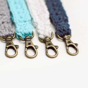 May include: Four keychains with different coloured crocheted straps and gold-toned metal clasps.