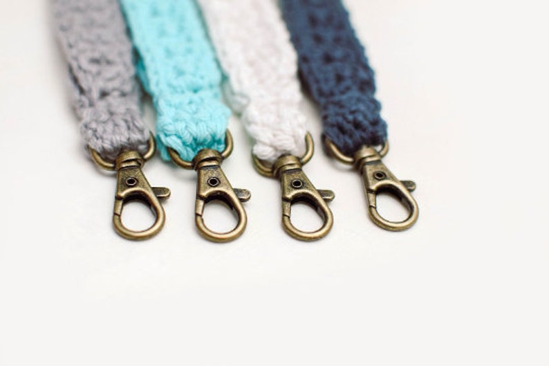 May include: Four keychains with different coloured crocheted straps and gold-toned metal clasps.