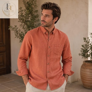 May include: A long-sleeved button-down shirt in a solid burnt orange color. The shirt features a classic collar, a single chest pocket on the left side, and light-colored buttons running down the center front placket. The fabric has a visible texture.