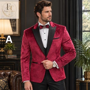 May include: A deep red velvet blazer featuring black satin peak lapels, a white button-down shirt, and a matching red velvet bow tie with a central silver-toned decorative pin. The jacket includes a black pocket square and black trim details.