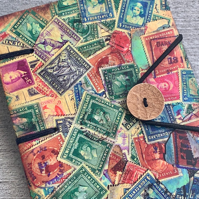 May include: A vintage-style notebook cover with a collage of colorful postage stamps featuring the text "Newfoundland" and various denominations. The stamps are arranged in a random pattern and have a faded, distressed look.