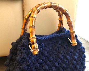 Handmade crochet bag in wool with bamboo handles and leather base.