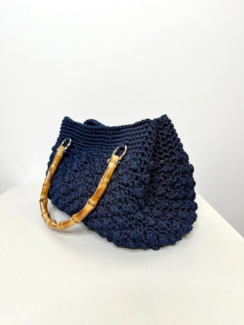 May include: A navy blue crocheted tote bag with bamboo handles.