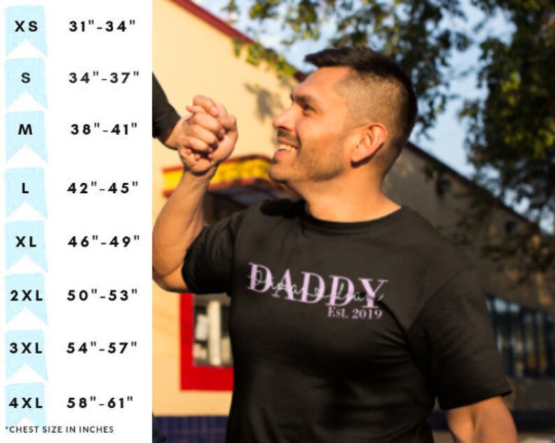 以下が含まれることがあります： 紫色の書体で「DADDY」と書かれた黒いTシャツで、「Est. 2019」という文字が下にあります。インチで胸囲のサイズ表が示されています。