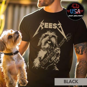 Op de afbeelding: Zwart T-shirt met een afbeelding van een hond met een zonnebril die een elektrische gitaar bespeelt. De tekst "REESA" staat boven de hond.