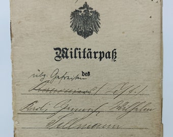 Puede incluir: Un documento de pase militar vintage con un emblema de águila alemana y el texto "Militärpass" en letras negras. El documento está fechado "Jahresklasse 19..." y tiene una firma manuscrita en la parte superior.