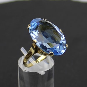Puede incluir: Un anillo de oro con una gran piedra preciosa ovalada de color azul claro.