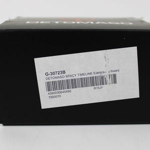 May include: A black rectangular product box with the brand name DETOMASO printed in white on the top edge. A white rectangular label is affixed to the front, featuring the text G-30723B, DETOMASO SPACY TIMELINE Edelstahl schwarz, and a barcode.