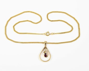 May include: Gold-toned necklace with a teardrop pendant. The pendant features a small, oval, dark red gemstone. The chain is a delicate, linked design. The necklace is displayed on a white background.