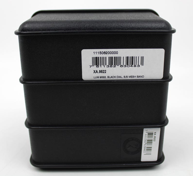 K&ouml;nnte beinhalten: Schwarze Uhrenbox mit einem wei&szlig;en Etikett mit der Aufschrift "111506200000", "7 811382 830483", "XA.9522", "LUM 9522, BLACK DIAL, S/S MESH BAND".