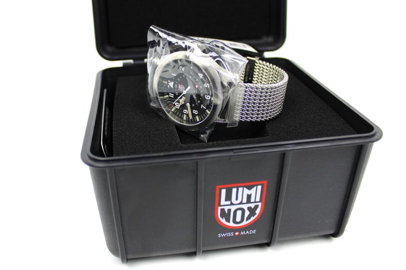 K&ouml;nnte beinhalten: Eine schwarze Luminox-Uhr mit schwarzem Zifferblatt und silbernen Zeigern und Markierungen. Die Uhr befindet sich in einem schwarzen Kunststoffgeh&auml;use mit dem Luminox-Logo auf der Vorderseite. Die Uhr hat ein silbernes Mesh-Armband.