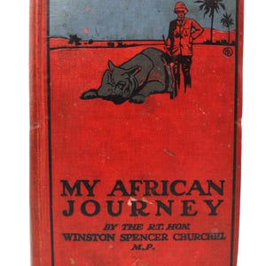 Pode incluir: Capa de livro vintage para "My African Journey" de Winston Spencer Churchill. A capa vermelha apresenta um céu azul e uma ilustração de rinoceronte. O título e o nome do autor são exibidos.