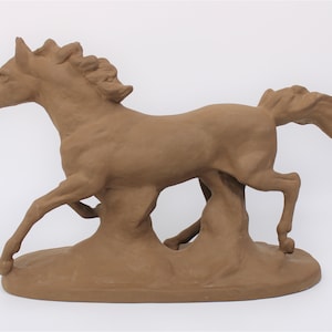 May include: A brown ceramic sculpture of a horse running. The horse is in mid-stride with its head turned to the side and its tail flowing behind it. The sculpture is on a rectangular base.