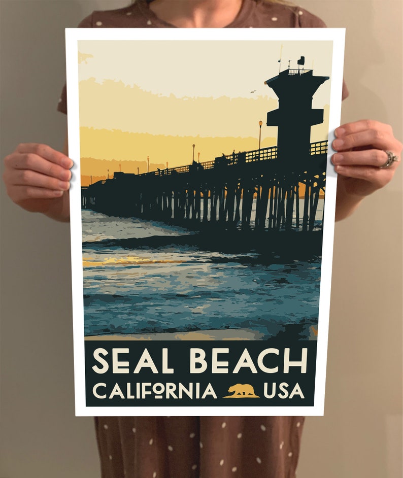 Puede incluir: Un cartel de viaje de estilo vintage con la silueta de un muelle que se extiende hacia el oc&eacute;ano al atardecer. El texto "SEAL BEACH CALIFORNIA USA" est&aacute; impreso en la parte inferior del cartel.
