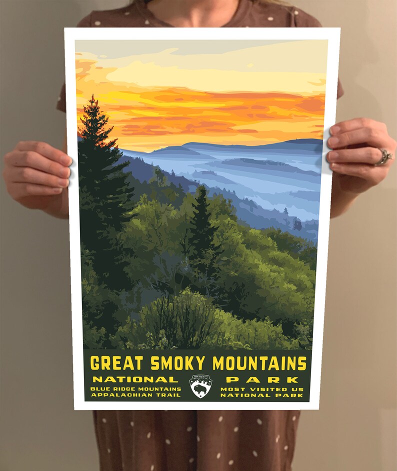 Op de afbeelding: Een vintage poster met een schilderachtig uitzicht op het Great Smoky Mountains National Park. De poster heeft een gele en oranje zonsondergangshemel met blauwe en paarse bergen in de verte. De tekst "Great Smoky Mountains National Park" staat in gele letters onderaan de poster. De tekst "Blue Ridge Mountains Appalachian Trail" staat in kleinere gele letters onder de naam van het park. De tekst "Most Visited US National Park" staat in kleinere gele letters onder de naam van het park.