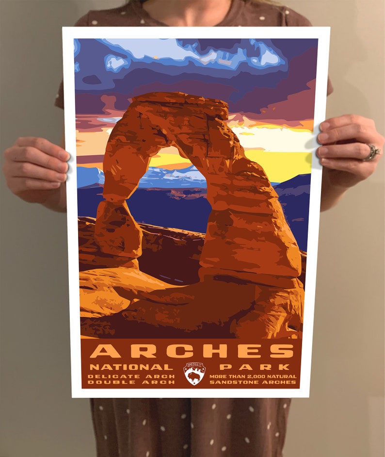 May include: A vintage-style poster featuring a scenic view of Delicate Arch in Arches National Park, Utah. The poster has a sunset sky with orange, yellow, and purple hues. The text reads "Arches National Park" with the park logo and "Delicate Arch, Double Arch, More than 2,000 Natural Sandstone Arches."