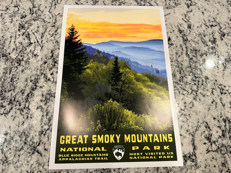 Op de afbeelding: Een vintage poster met een schilderachtig uitzicht op het Great Smoky Mountains National Park bij zonsondergang. De poster heeft een groene achtergrond met gele tekst die "Great Smoky Mountains National Park" en "Blue Ridge Mountains Appalachian Trail" linksonder en "Most Visited US National Park" rechtsonder staat.
