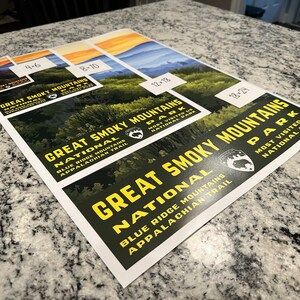 Op de afbeelding: Een set van vier posters van het Great Smoky Mountains National Park. De posters hebben een donkergroene achtergrond met gele tekst en een zwart berenlogo. De tekst op de posters luidt "Great Smoky Mountains National Park" en "Blue Ridge Mountains Appalachian Trail". De posters zijn verkrijgbaar in vier formaten: 4x6, 8x10, 12x18 en 18x24.