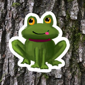 May include: A green frog with big, round, yellow eyes and a pink tongue sticking out. The frog is wearing a pink collar and is sitting on a tree trunk.